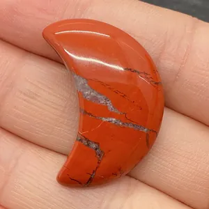 Gros plan sur une pierre de jaspe rouge en forme de croissant au fini lisse et naturel