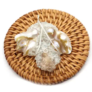 Pendentif artisanal en perles baroques et cristal enroulé de fil sur un tapis tissé