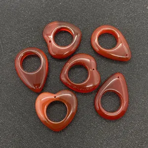 Detailed view of red agate stone pendants in heart and teardrop shapes for DIY jewelry