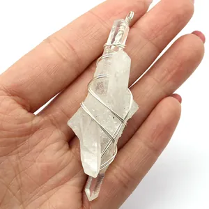 Handmade wire wrapped natural white crystal point pendant held in hand for size