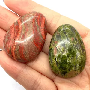 Pierres de jaspe rouge et unakite polies tenues en main pour référence de taille