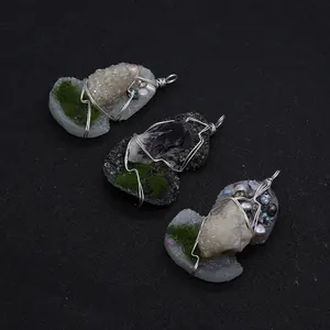Macro detail of handmade wire-wrapped crystal pendants with pearls and natural moss