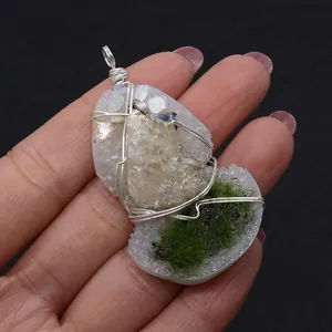 Macro shot of handmade silver wire-wrapped quartz crystal pendant with green moss accents