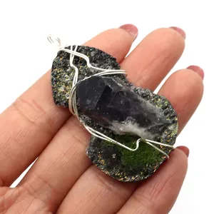 Handmade silver wire wrapped natural amethyst crystal point pendant held in palm