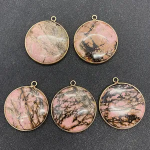 Détail de cinq pendentifs ronds en rhodonite rose avec bordure dorée et petit anneau