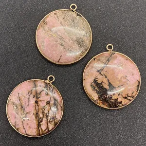 Détail macro de trois pendentifs ronds en pierre naturelle rose avec bordure dorée