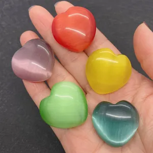 Vue détaillée de cinq pierres œil-de-chat multicolores en forme de cœur dans la main