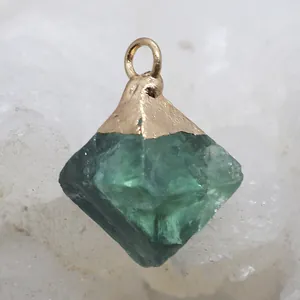 Macro shot of natural green crystal prism pendant with golden metal cap for jewelry making