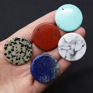 Macro shot of assorted 30mm natural stone round pendants held by hand for DIY jewelry making