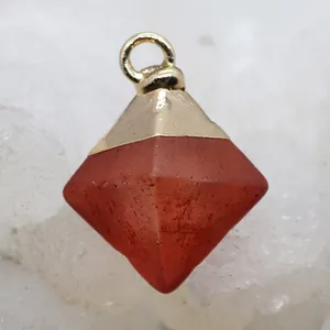 Macro shot of a red carnelian pyramid stone pendant with a polished gold metal cap