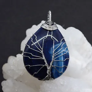 Macro detail of silver Tree of Life wire wrapped teardrop blue agate stone pendant