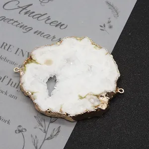 Makroaufnahme von weißem Druzy-Naturstein mit Goldrand und zwei Verbindungsringen