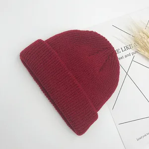 Détail du bonnet en maille rouge foncé montrant la texture côtelée et le large bord plié