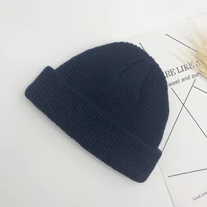 Détail du bonnet en maille bleu marine avec bord roulé sur fond de style minimaliste