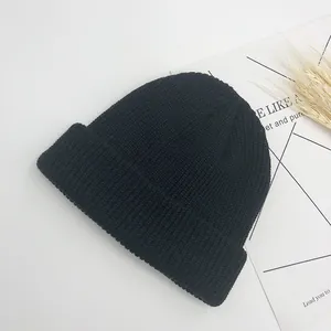 Détail du bonnet en maille côtelée noire avec large revers et texture douce en gros plan