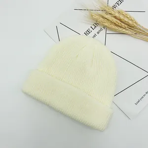 Détail du bonnet en maille blanc crème montrant la texture côtelée et le bord replié
