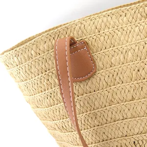 Detail of bohemian striped woven tote bag showing straw texture and leather stitching