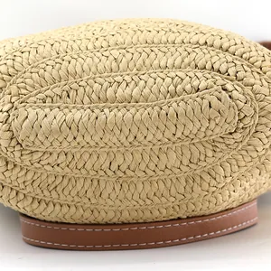 Macro detail of hand-woven straw texture and brown leather strap with white stitching