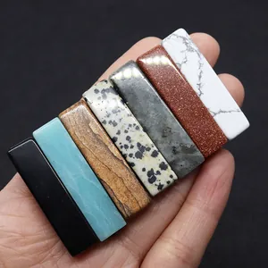 Mano sosteniendo cuentas rectangulares de piedra natural en varios colores