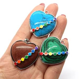 Three heart-shaped gemstone pendants with silver edging held in hand for size display