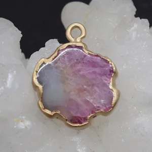 Macro shot of pink natural stone pendant with gold plating on a white crystal cluster