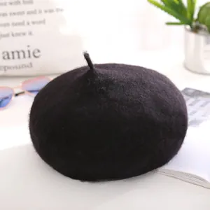 Classic black wool beret with top stem detail shown in a stylish minimalist setting