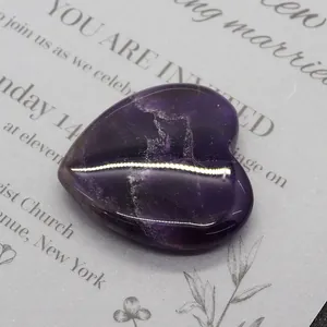 Macro shot of polished 40mm heart-shaped natural amethyst stone on invitation card