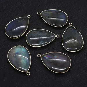 Macro view of six teardrop labradorite pendants with gold plated edges and blue fire flashes
