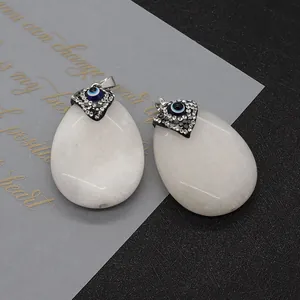 Détail de deux pendentifs ovales en pierre blanche avec œil maléfique en strass argentés