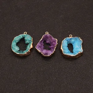 Close-up of three natural druzy agate pendants in green, purple and blue with gold plating