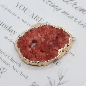 Macro detail of irregular red stone pendant with polished gold wavy edges and hanger