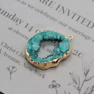 Macro shot of irregular blue agate geode pendant with gold rim on textured paper