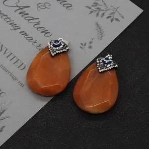 Detail of drop-shaped orange stone pendants with Evil Eye crystal-encrusted metal mount