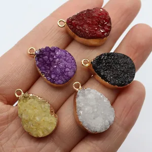 Waterdrop-shaped natural druzy stone pendants with gold metal edges held in hand