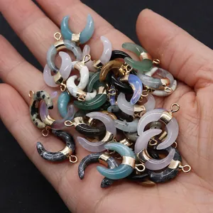Gros plan de pendentifs en pierre en forme de croissant avec monture dorée et anneau