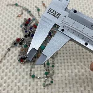Close-up of caliper measuring faceted natural stone beads on a silver chain link