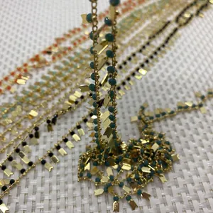 Close-up of colorful faceted crystal bead chains with golden metal arrow tags for DIY jewelry