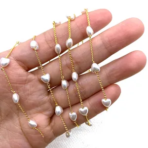 Golden twist chain necklace with heart-shaped white pearls shown on a hand for scale