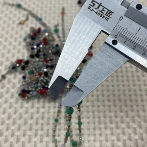 Macro shot measuring 3mm natural stone beads on a silver chain with a digital caliper