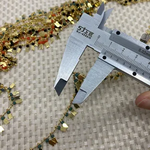 Caliper measuring a butterfly metal charm on a gold beaded crystal chain accessory