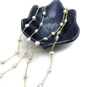 Golden chain necklace with white heart pearls displayed on a black decorative tray