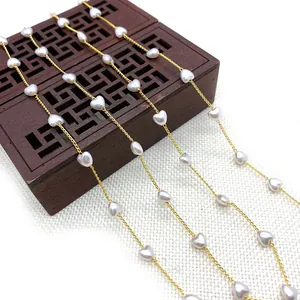 Golden twist chain with white heart-shaped pearls on a vintage wooden box
