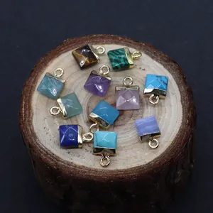 Macro view of square natural gemstones with gold hooks on a rustic wood slice