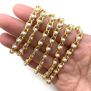 Golden twist chain with white ABS pearls for DIY necklace making shown in hand