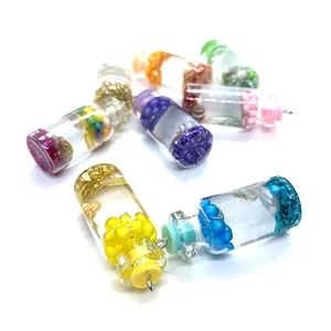 Vue macro de mini bouteilles colorées en verre avec charmes en résine pour bijoux DIY
