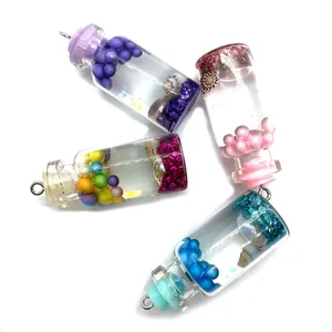 Détail de quatre pendentifs bouteilles en verre 16x42mm avec bulles de résine et coquillages