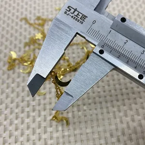 Macro shot measuring 1cm golden star and moon charms on chain using a digital caliper