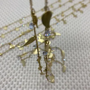 Macro detail of gold twist chain with leaf charms and sparkling zircon accents