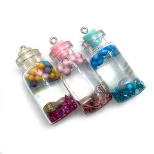 Vue détaillée de trois pendentifs en verre 16x42mm avec coquillages en résine et paillettes