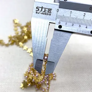 Macro detail showing a 3mm pink faux pearl being measured on a gold star link chain